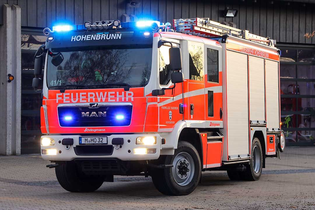 Löschfahrzeug der Feuerwehr Hohenbrunn mit Blaulicht vor dem Gerätehaus in der Dämmerung.