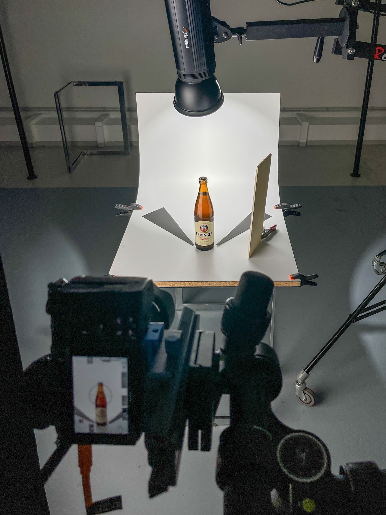 Studio-Setup mit Erdinger Weißbier-Flasche, Dauerlicht von oben und schwarzen Abschattern für die Kantenzeichnung am Glas.