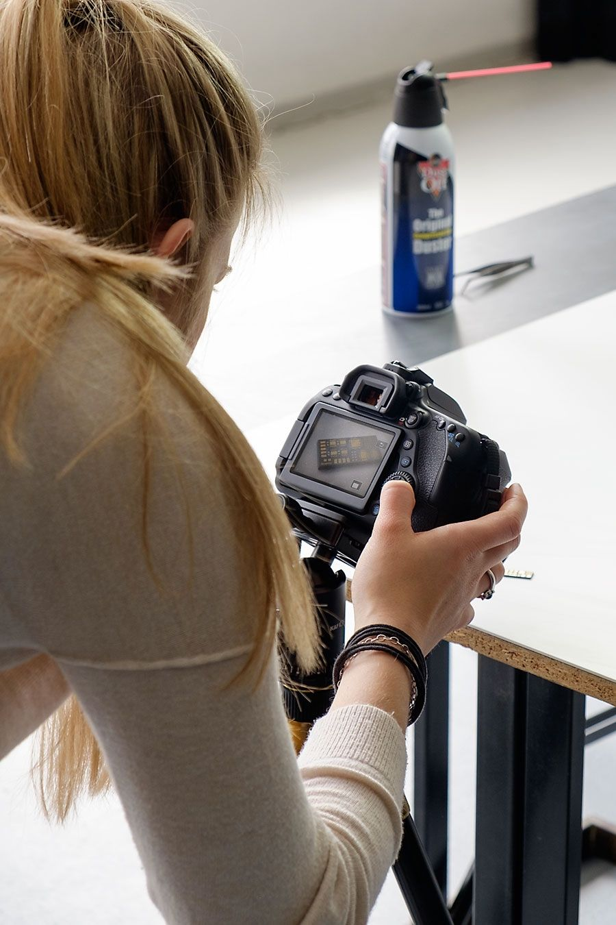 Teilnehmerin kontrolliert die Kameraeinstellungen auf dem Display einer DSLR während des Produktfotografie-Workshops.