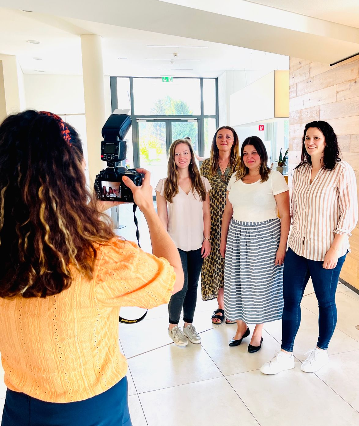 Portraitshooting mit Aufsteckblitz auf der Kamera – vier Kolleginnen posieren im Foyer der Molkerei während der Fotografie-Schulung.